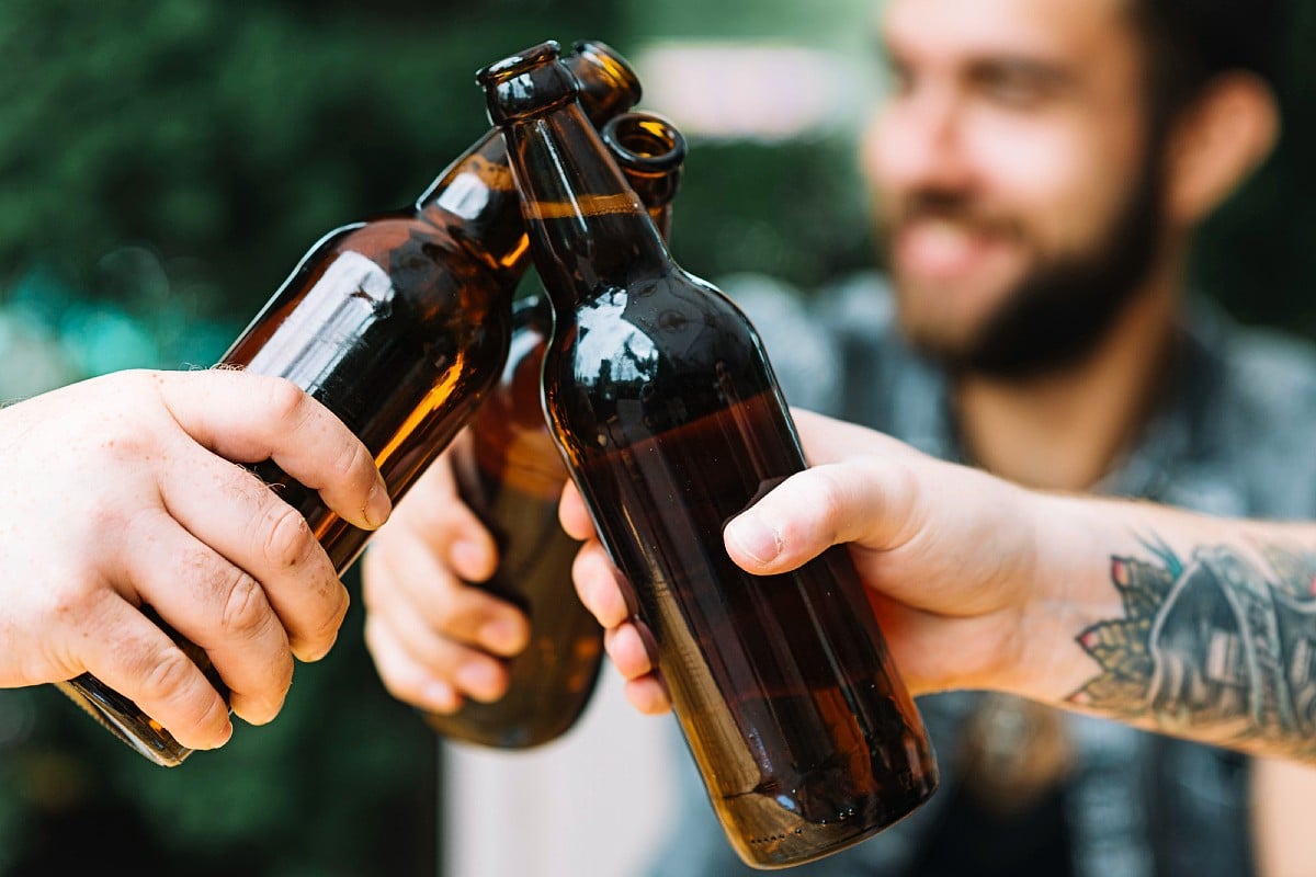 Tías chocando botellas de cerveza en una fiesta en el jardín